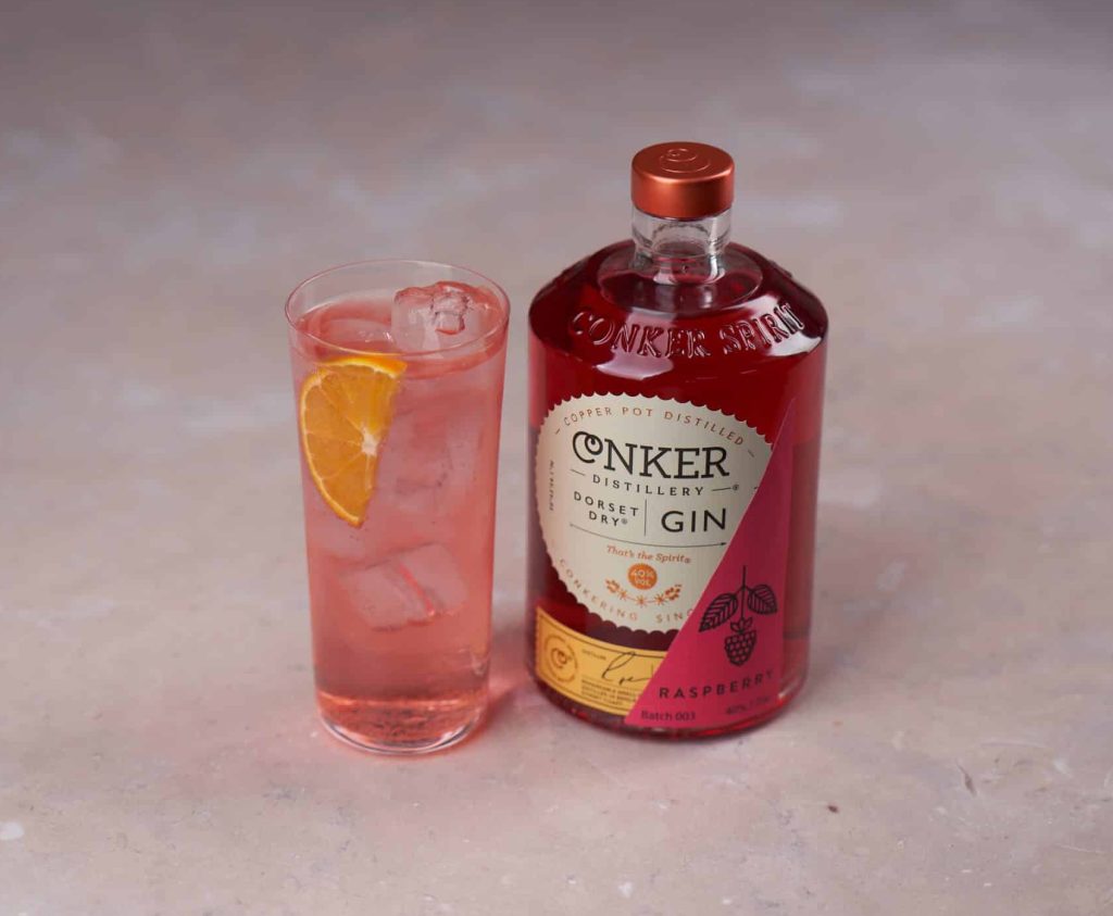 A bottle of Conker Raspberry Gin next to a Raspberry G&T